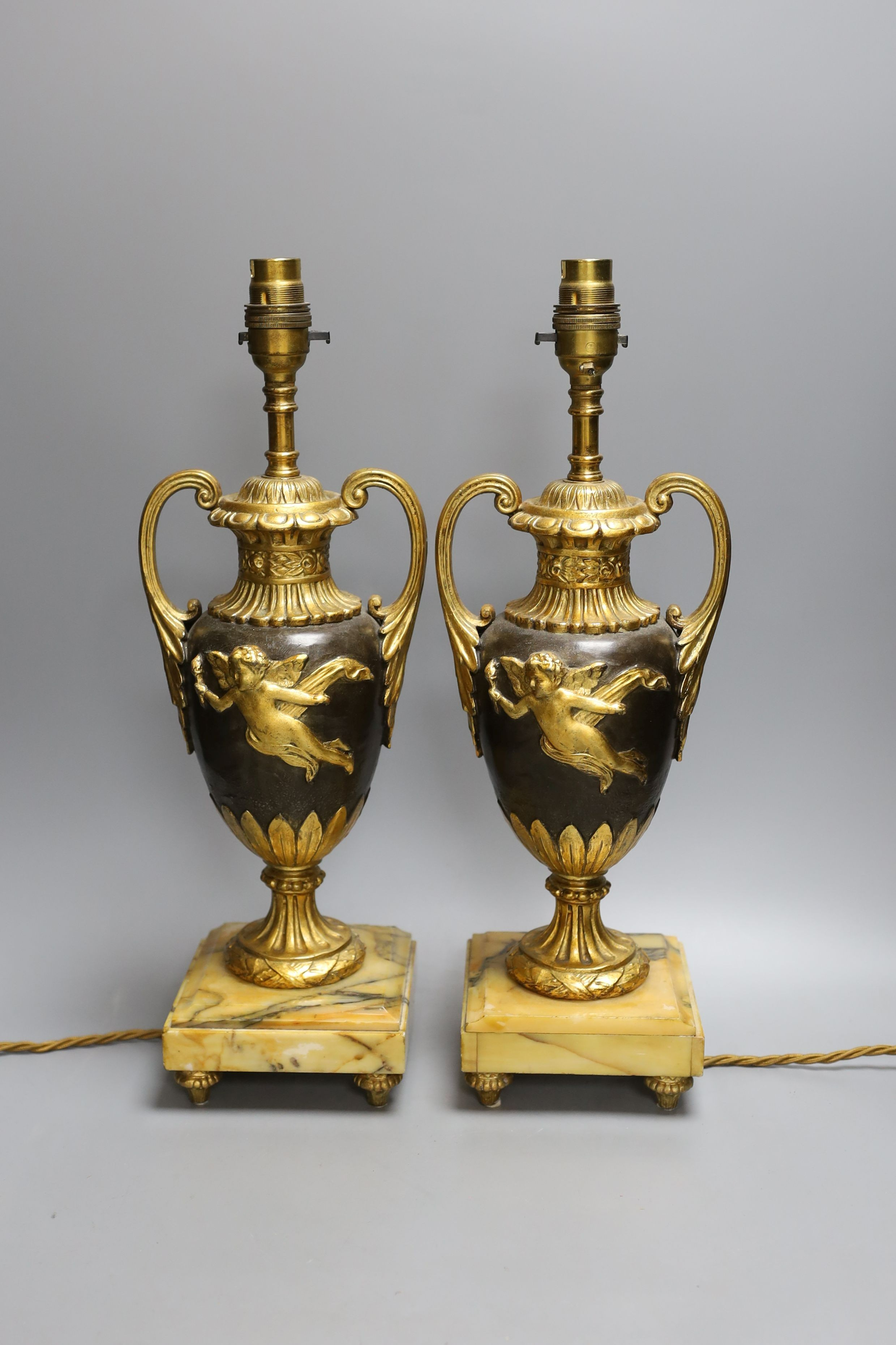 A pair of ornate guilt vase style lamps on marbled base, together with a seated cherub table lamp, 45cm tall, (3)